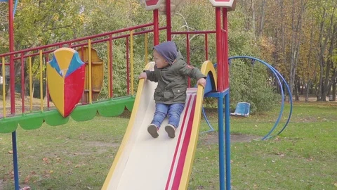 Cheerful boy riding down the hill on playground Видео 96250287