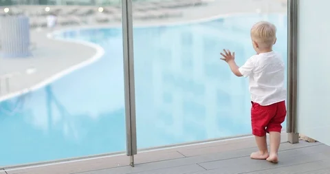 A cheerful boy runs around with candy on a summer terrace against a pool backgro Stock Footage 97075968