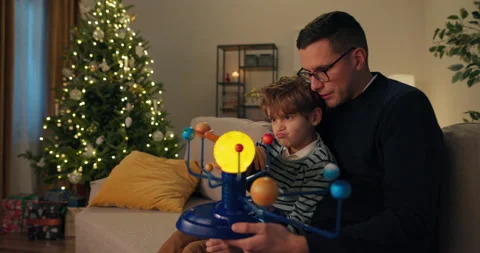 Cheerful boy sitting on the couch with uncle. They will look at model of the Stockbeeldmateriaal 210496241