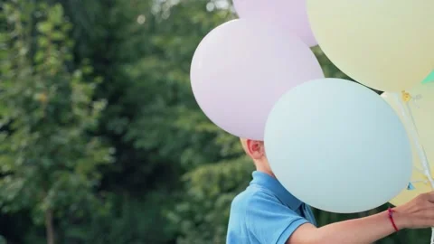 Cheerful boy is spinning with inflatable balls in his hands. Video stock 228571917