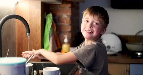 Cheerful boy washing hands in kitchen sink and drying with napkin Stock Footage 294321471