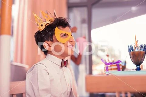 Cheerful boy wearing mask and paper crown while visiting carnival Stock Photos