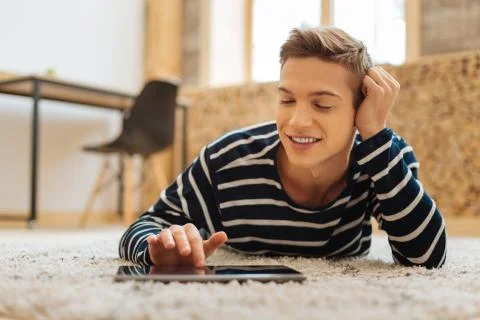 Cheerful boy working on tablet while lying on the floor Stock Photos