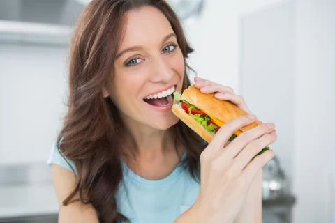 Cheerful brunette eating sandwich Stock Photos
