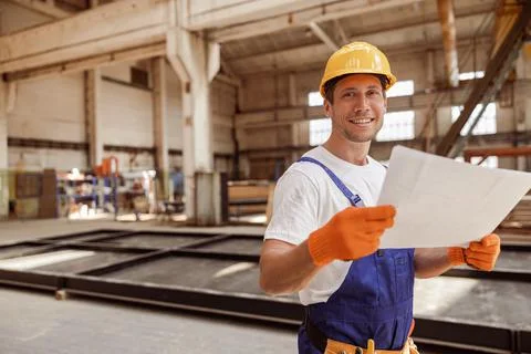 Cheerful builder studying architectural plan at construction site Stock Photos