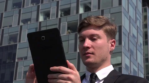 Cheerful businessman outdoors sliding tablet close up head face office building Stock Footage