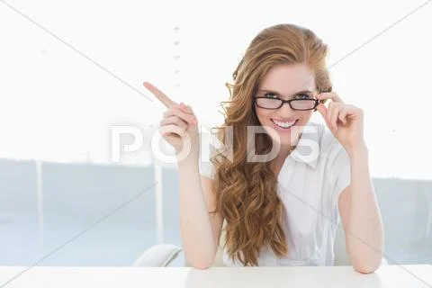 Cheerful businesswoman pointing to side in office Stock Photos