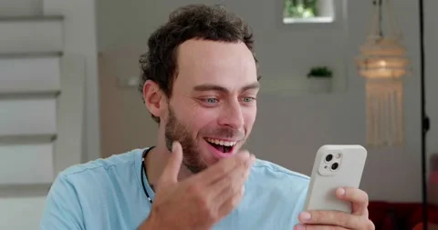 Cheerful Caucasian guy using smartphone, writing text messages, scrolling news Stock Footage 219951825