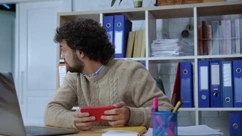 Cheerful caucasian office worker playing mobile game app on smartphone Stock Footage 118470864
