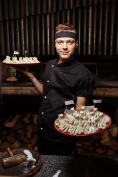 Cheerful chef posing with a serving of Khinkali. Georgian national traditional Stock Photos