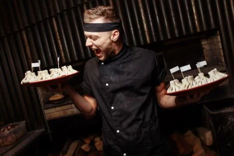 Cheerful chef posing with a serving of Khinkali. Georgian national traditiona Stock-Fotos