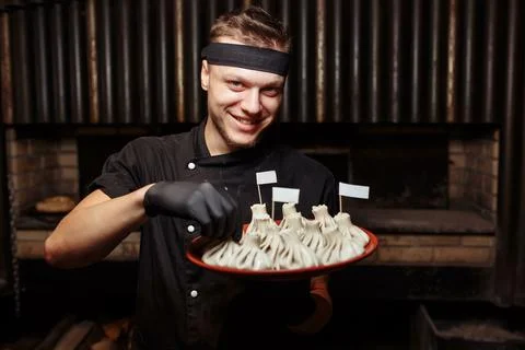 Cheerful chef posing with a serving of Khinkali. Georgian national traditional Stock Photos