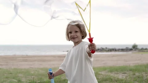 A cheerful child blows soap bubbles outdoors. Stock Footage 283763749