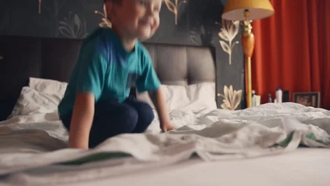 Cheerful child boy prancing on the bed Stock Footage 124315343
