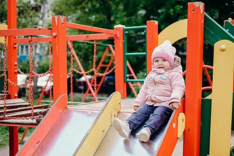 A cheerful child is going to roll down a slide on the playground Stock Photos