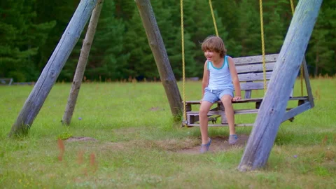 A cheerful child laughs while swinging on a swing. Outdoor play in the park. Stock Footage 219318003