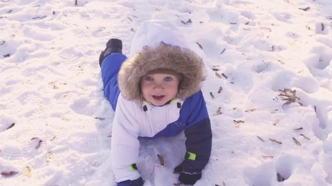 Cheerful child playing in the first snow in winter. Year old baby boy  Stock Footage 70153010