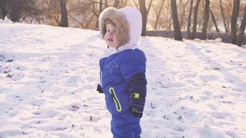 Cheerful child playing in the first snow in winter. Year old baby boy  Stock Footage 70153035