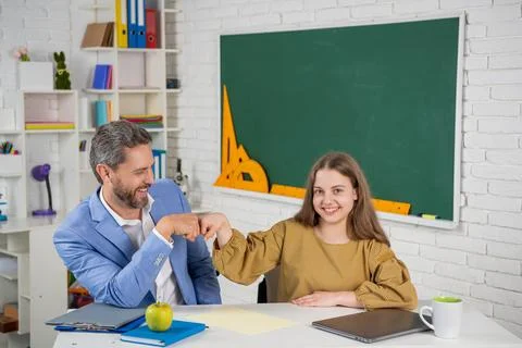 Cheerful child study in classroom with tutor. fist to fist Stock Photos