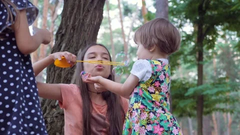 Cheerful children with bubbles on the yard, forest, park. Beautiful caucasian Vídeos de archivo 138636446