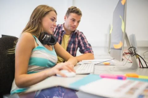 Cheerful classmates doing an assignment together in the computer room Stock Photos