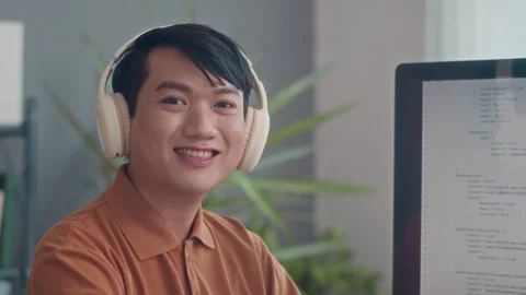 Cheerful Coder in Headphones Smiling at Camera Stock Footage 265074174