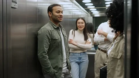 Cheerful colleagues discussing work project and riding in elevator in office Stock Footage 238373659