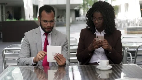 Cheerful colleagues using digital devices at cafe Stock Footage 114964196