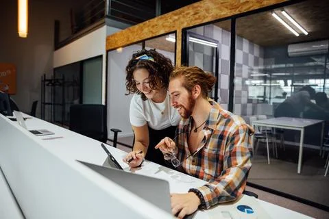 Cheerful colleagues working on project using gadgets Stock Photos