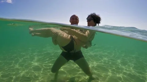 Cheerful couple having fun and laughing into the ocean, underwater shot Stock Footage 91586571