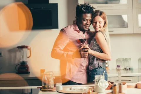 Cheerful couple turning to the table while hugging and smiling Stock Photos