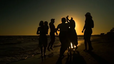 Cheerful crowd dancing on the beach. They jump in the sun. People are having fun Stock Footage 98953208