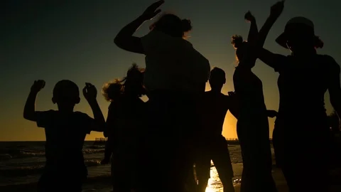 Cheerful crowd dancing on the beach. They jump in the sun. People are having fun Stock Footage 98953320