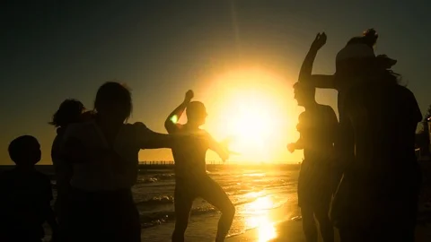 Cheerful crowd dancing on the beach. They jump in the sun. People are having fun Stock Footage 98953409