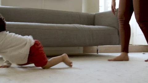 Cheerful curly-haired boy crawling on floor to ball. 動画素材 154934657