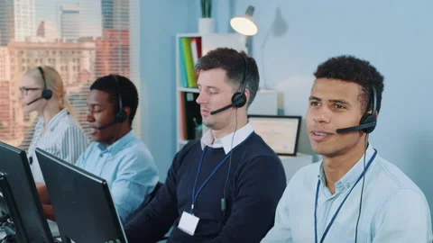 Cheerful customer support agent of mixed ethnicity talking on phone with a Stock Footage 153471462