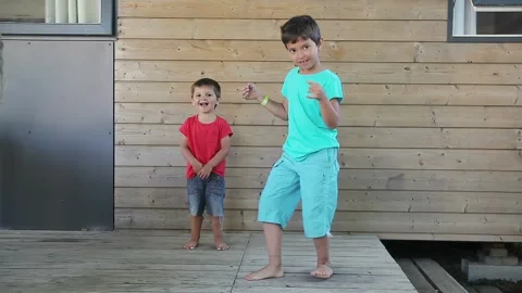 Cheerful cute boy dancing with his small brother a little awkward but having fun Stock Footage 310274382