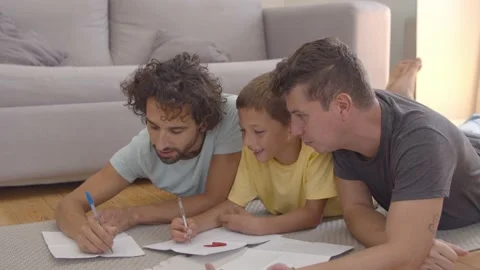 Cheerful dads and son lying on floor and... | Stock Video | Pond5