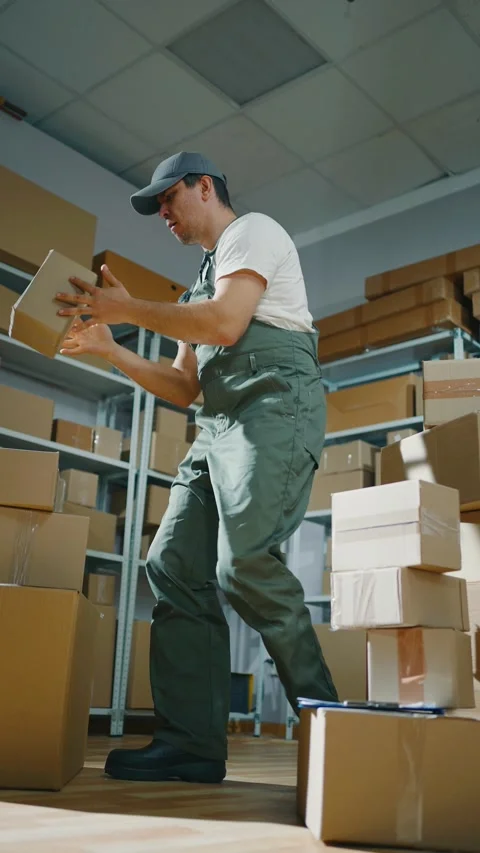 A cheerful dancing loader man in a box warehouse vertical video Stock Footage 276205162