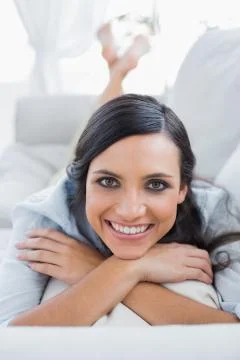 Cheerful dark hair woman lying on the couch Stock Photos