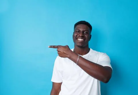 A cheerful dark-skinned man with a beaming smile points his finger to the sid Stock Photos