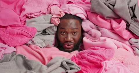 Cheerful dark skinned man covered with clothes busy decluttering wardrobe feels Stock Footage 157335814