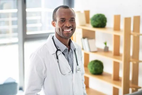 Cheerful dark-skinned practitioner keeping stethoscope Stock Photos