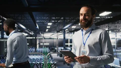 Cheerful data center admin doing maintenance tasks on tablet Stock Photos