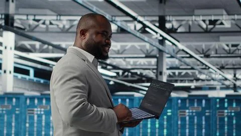 Cheerful data center system administrator reviews code for automation scripts Stock Photos