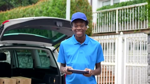 Cheerful delivery african man using tablet while working with van Stock Footage 284420259