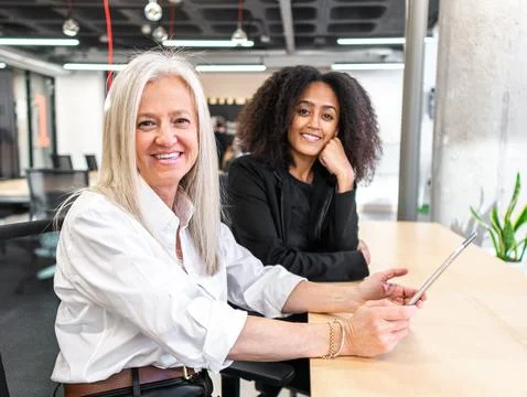 Cheerful diverse colleagues using tablet in modern workspace Stock Photos