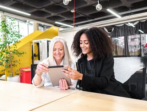 Cheerful diverse colleagues using tablet in modern workspace Stock Photos