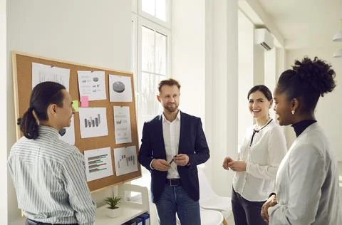 Cheerful diverse office workers discuss financial risks and analyze charts and Stock Photos