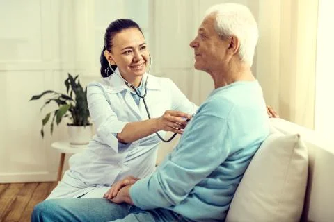 Cheerful doctor using stethoscope for checking lungs of elderly man Stock Photos